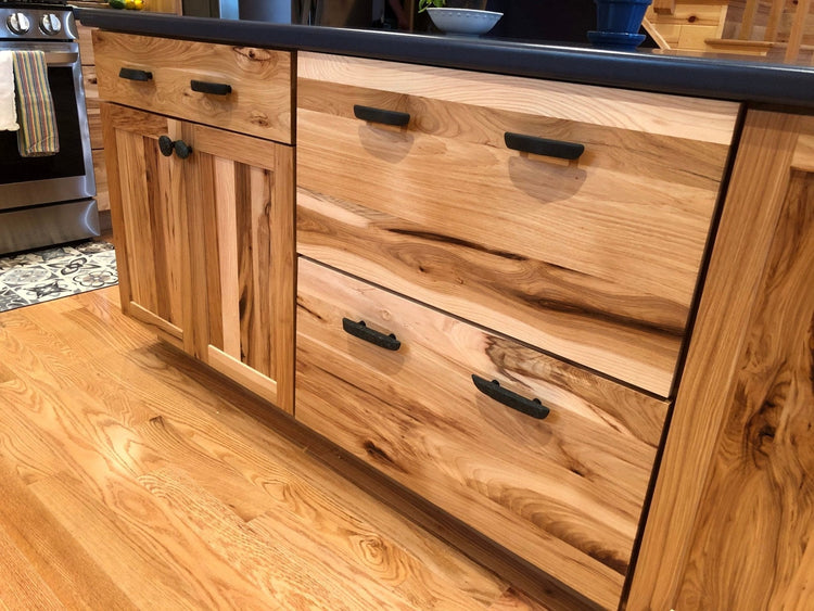 Natural wood cabinets with dark basalt rock cabinet knobs and pulls.