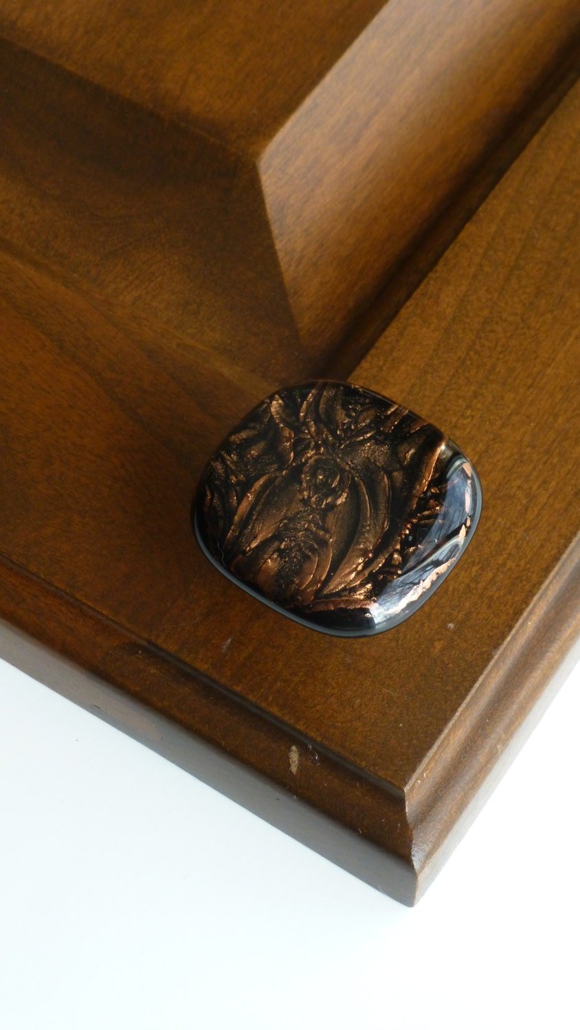 A handmade copper knob is installed and displayed on a cherry oak cabinet. Made in USA. Ann Ivory Studios
