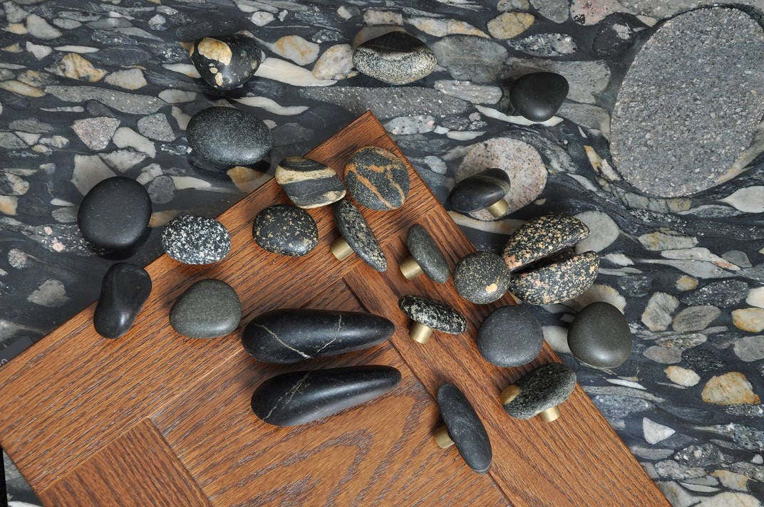 Multiple Stone Cabinet Knobs with Brass Base are being displayed on top of a cherry cabinet door.