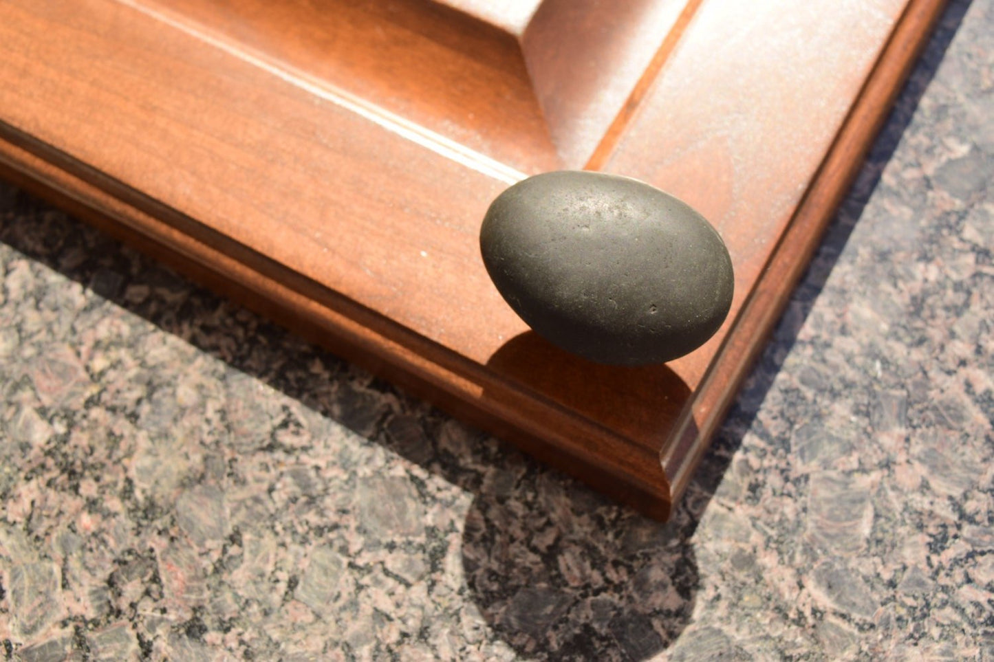 1 Stone Cabinet Knob installed on a dark cabinet door. - Brass Base - Natural Mountain Midnight - Ann Ivory Studios