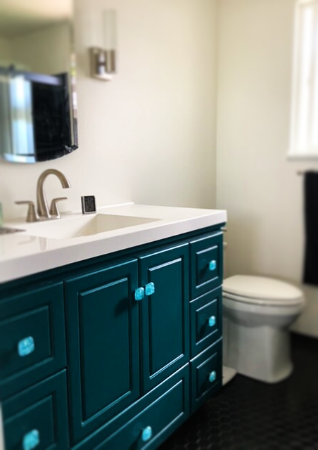 Bathroom vanity with blue and teal cabinet hardware.